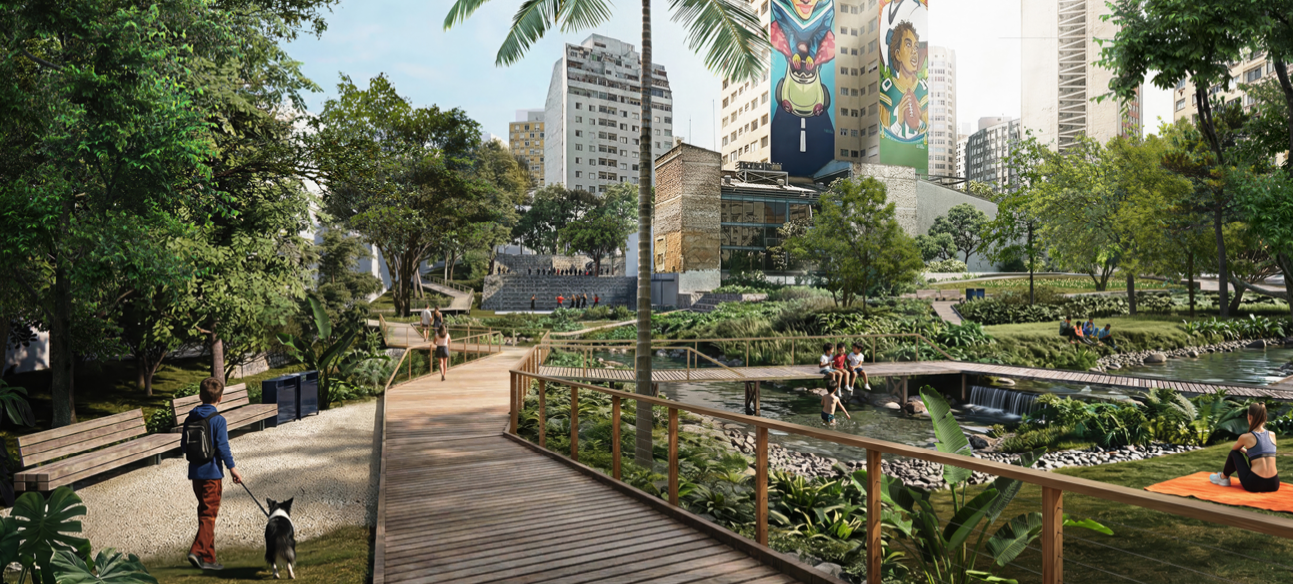 Parque urbano com passarela de madeira sobre um riacho, áreas verdes e árvores. Pessoas caminham, descansam e crianças brincam perto da água. Ao fundo, prédios altos com murais coloridos.